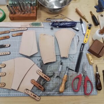 leather working station with tools and cut leather pieces